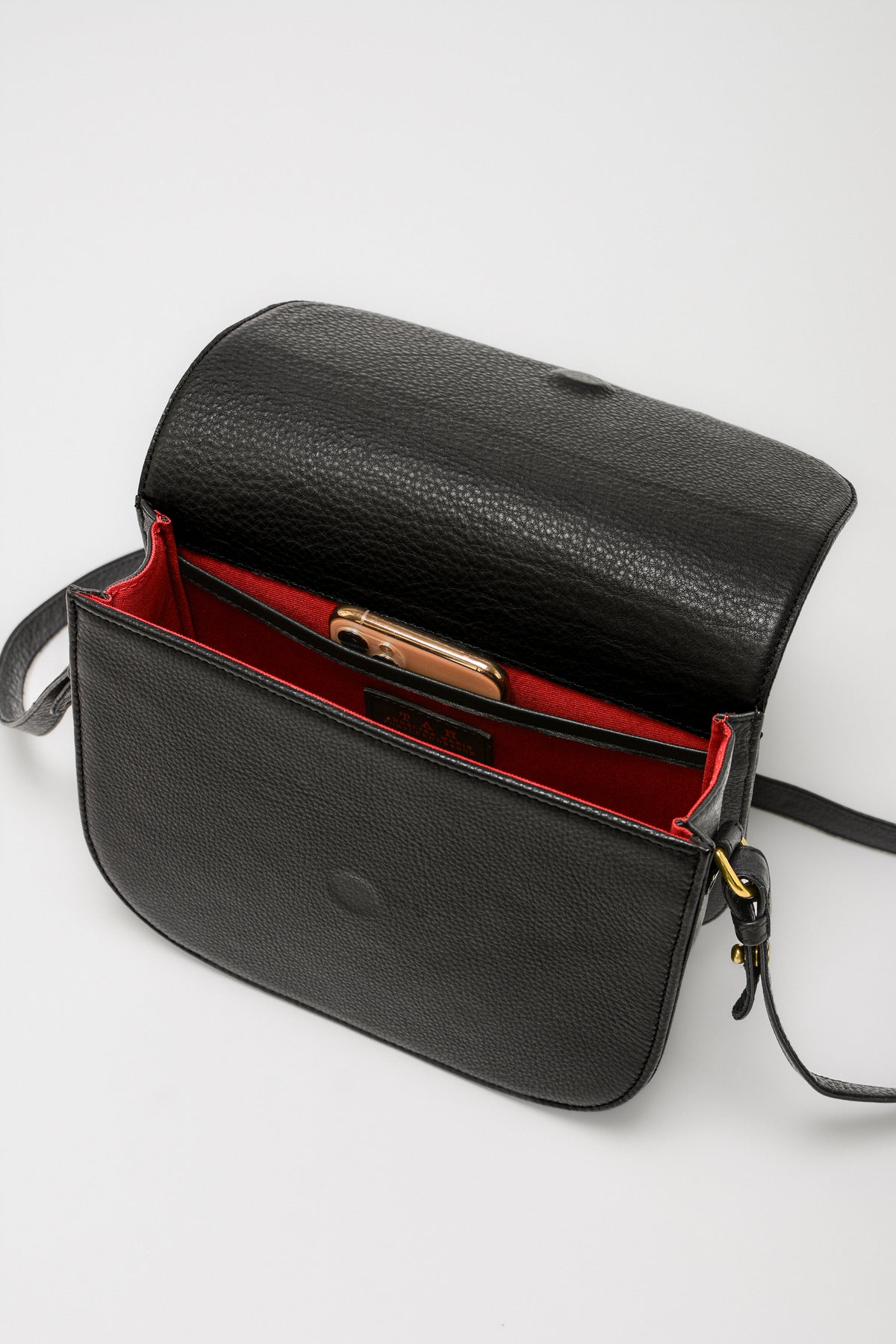 Black leather saddle handbag with red interior, showing the interior compartments