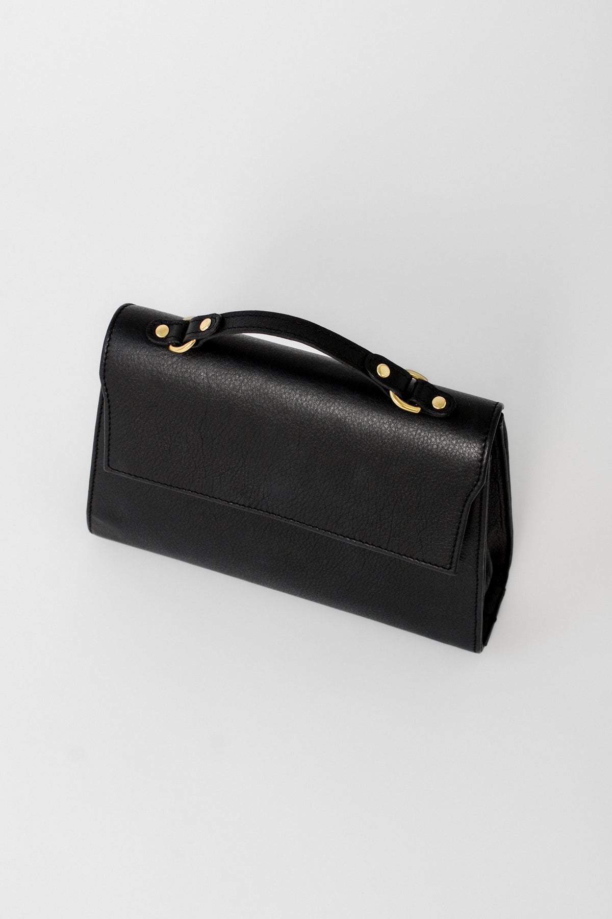 Back view of the black leather Carrie Petite top-handle bag, showcasing its clean, minimal design and structured silhouette for refined everyday or evening use.