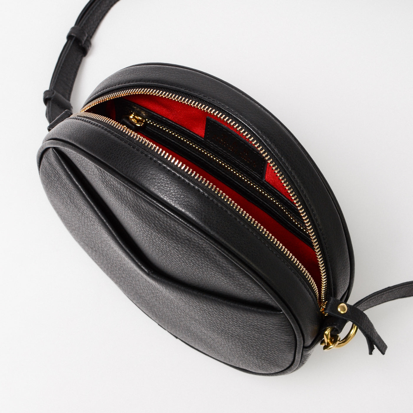 Circle Bag Crossbody in black full grain leather and gold hardware, showing the red interior lining and compartments