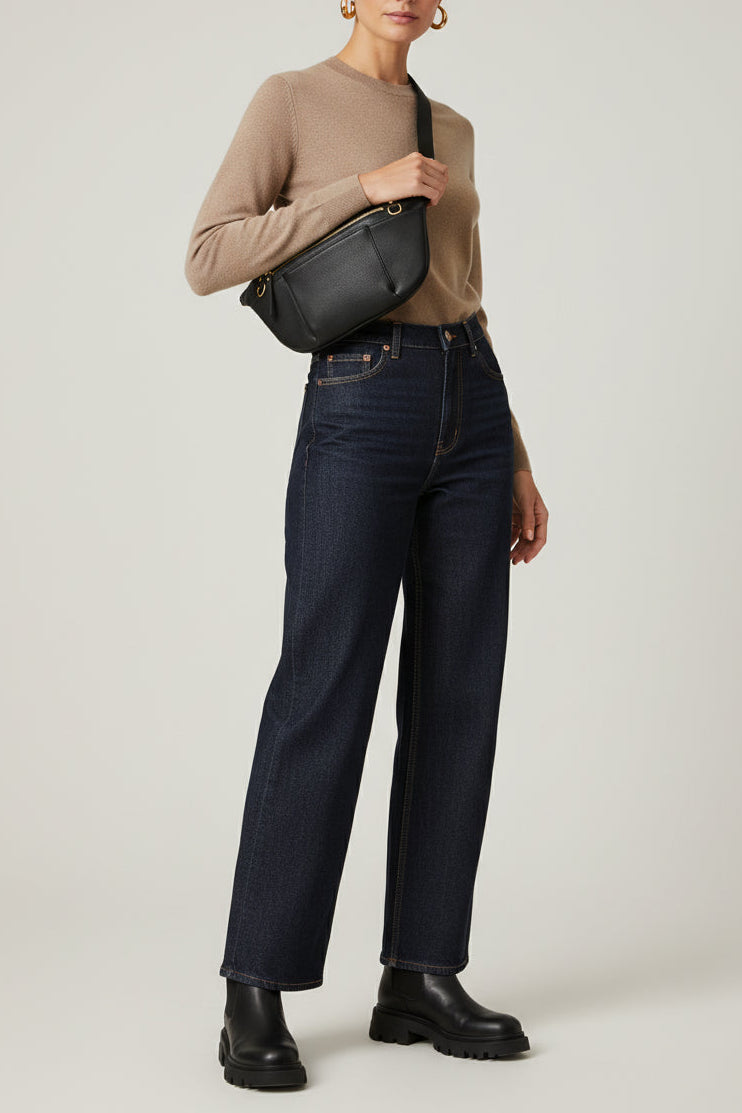 Black leather commuter sling bag worn crossbody, featuring an adjustable strap, zip compartments, and gold hardware, styled as a hands-free everyday bag for work, travel, and daily use.