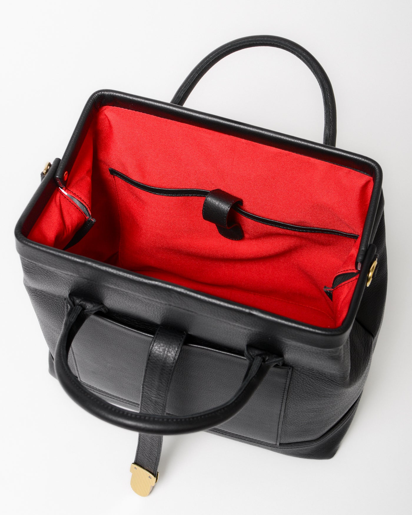 Handcrafted full-grain leather Doctor Bag with double handles, metal frame opening with red lining and tablet compartment. Top view of the interior 