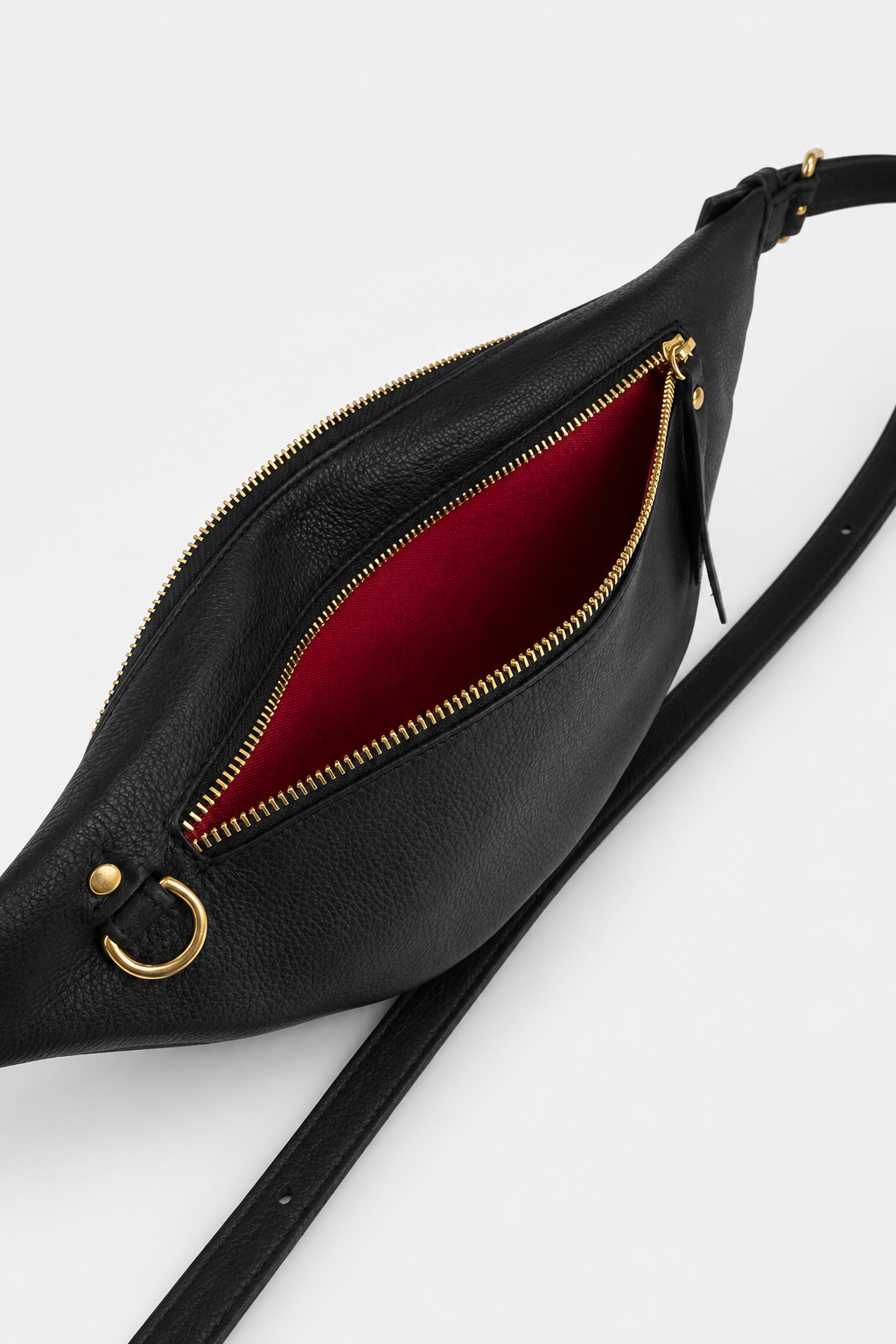 Nomad Fanny Pack in black full-grain leather with back compartment fully open, showcasing the signature red interior lining, gold zipper hardware, and spacious interior with adjustable strap visible.