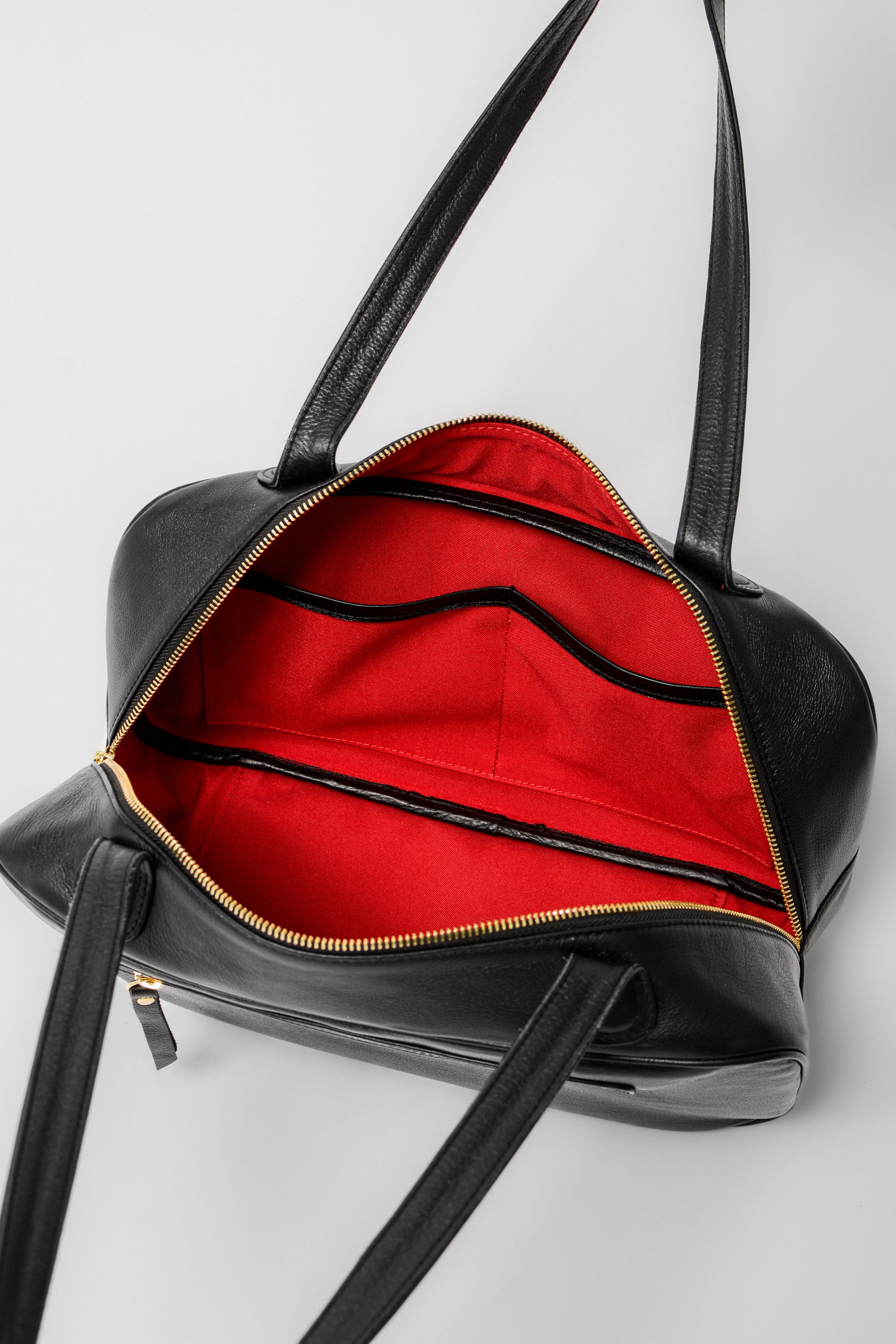 Interior view of the Ari Bowler Bag showing red lining with open organizer pockets designed to keep essentials neatly in place.