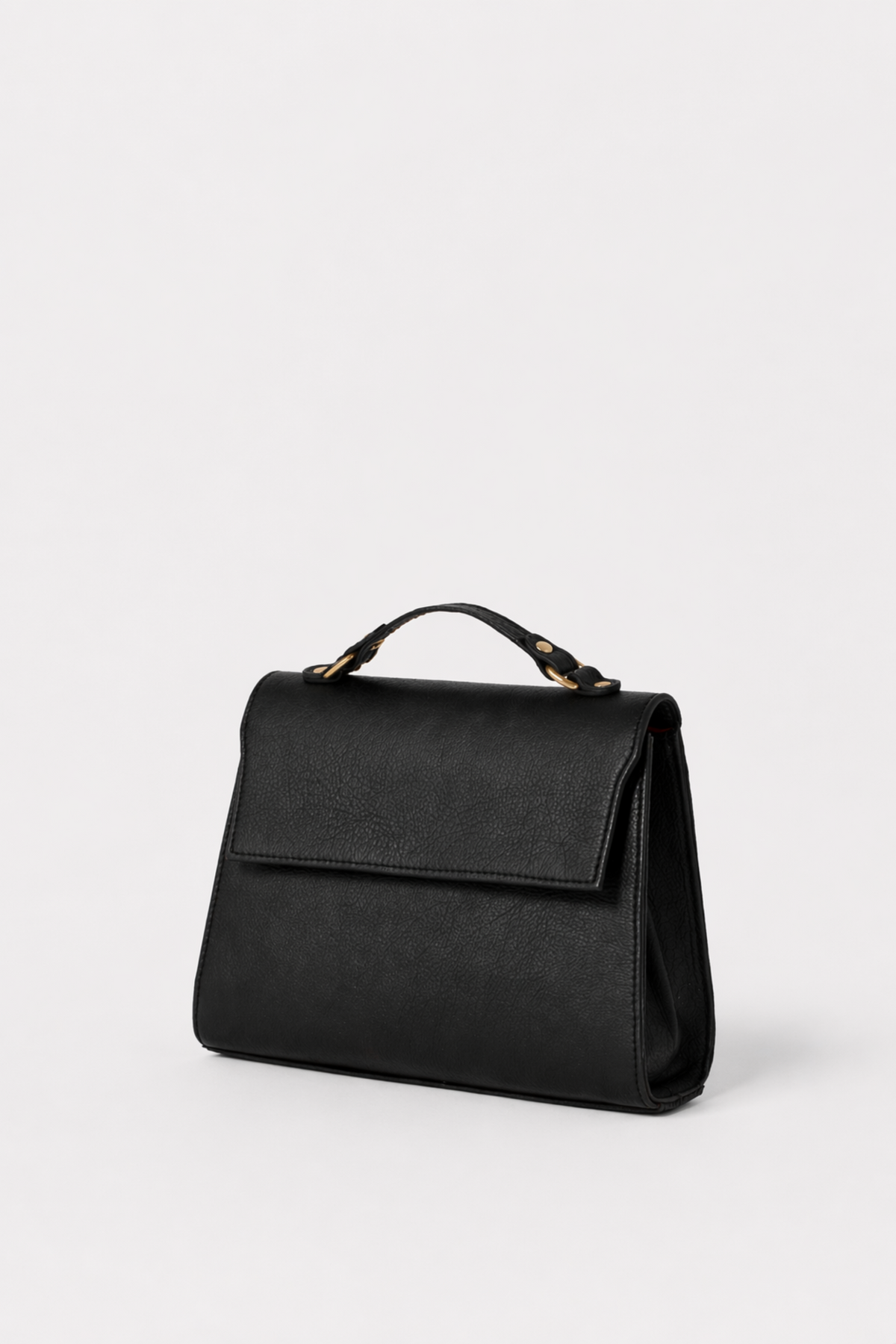 Black leather Carrie Petite top-handle bag with structured silhouette and flap closure, featuring gold hardware and a refined, minimalist design.