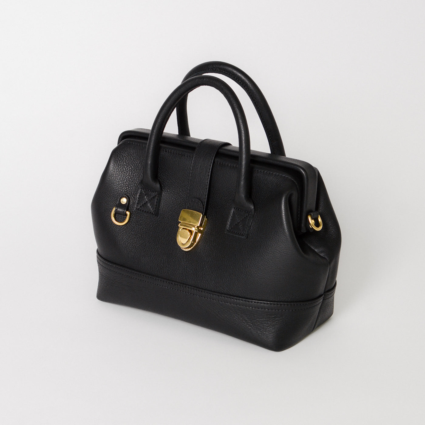 Front view of the Doctor Bag Petite in black leather, featuring structured top handles, a signature gold lock closure, and a clean, architectural silhouette.