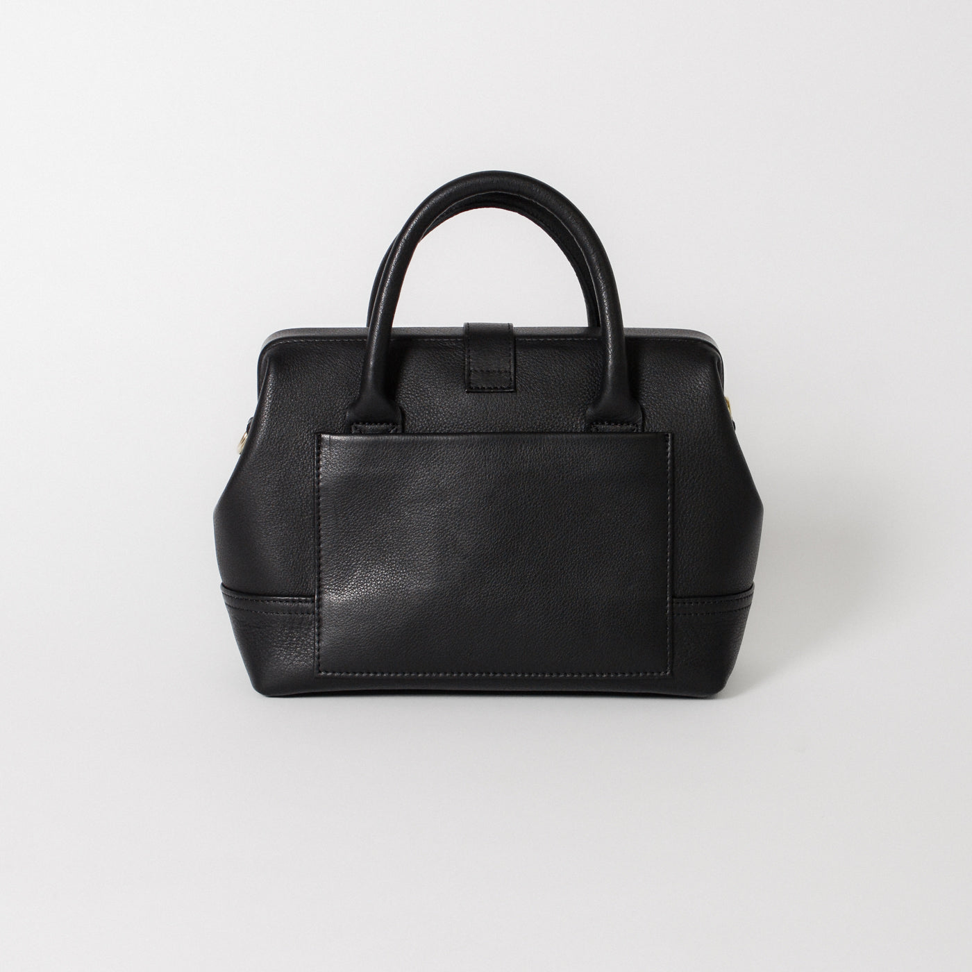 Back view of the Doctor Bag Petite in black leather, featuring a structured silhouette with a clean exterior pocket and top handles.