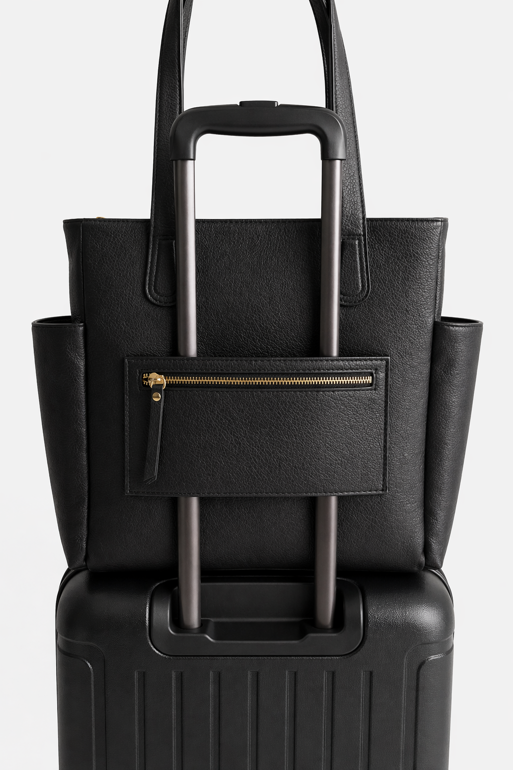 Black leather Emily Tote secured over a suitcase handle, featuring a back zip pocket that doubles as a luggage sleeve for easy travel.
