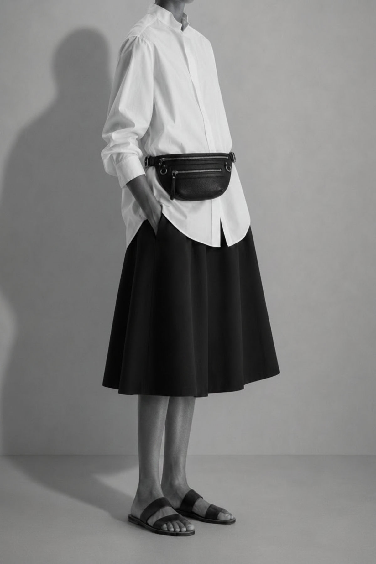 TAH Nomad black leather fanny pack worn at the waist with a white blouse and black skirt