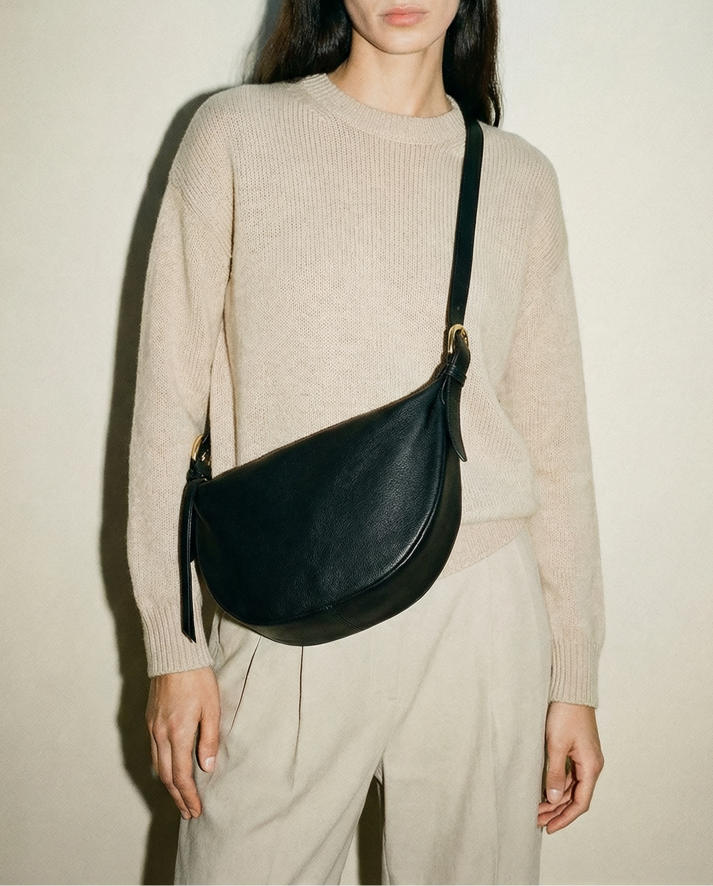 Model wearing the black leather Nova Sling Bag as a crossbody, featuring a curved silhouette, adjustable strap, and hands-free everyday design.