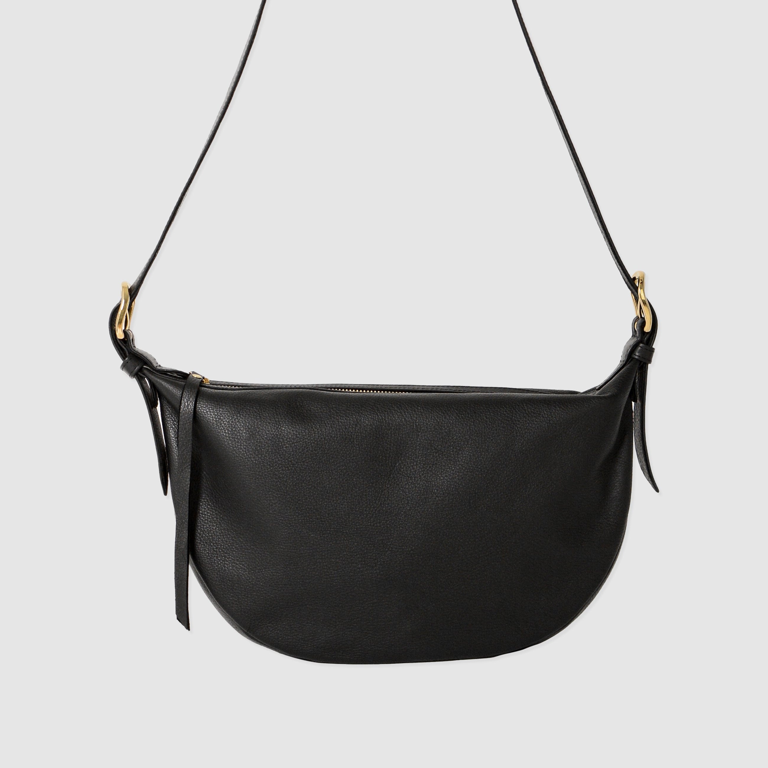 Black leather Nova Sling Bag featuring a curved silhouette, adjustable crossbody strap, and zip-top closure for everyday use.