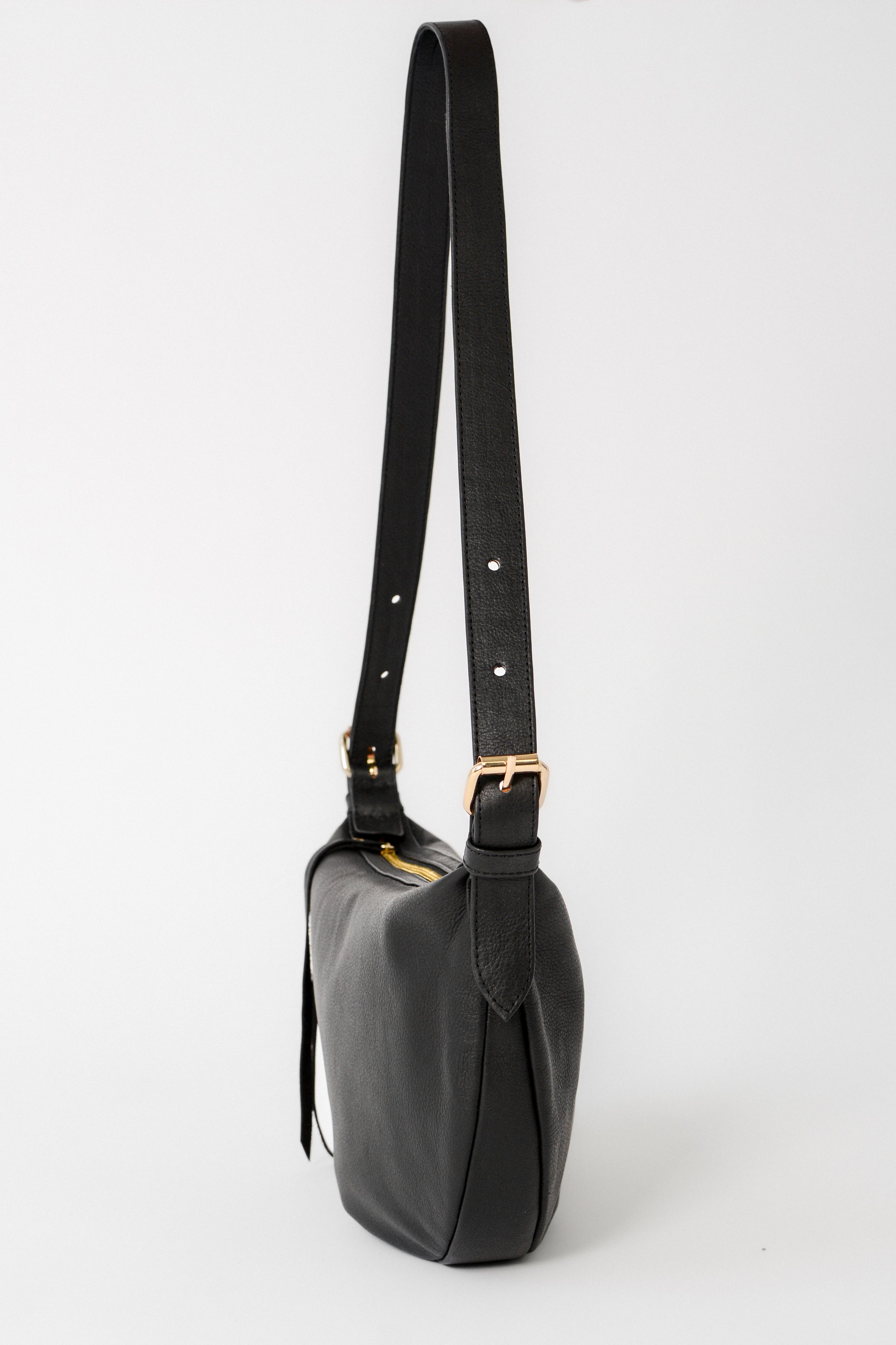 Side view of the black leather Nova Sling Bag highlighting the adjustable strap and structured silhouette for crossbody wear.