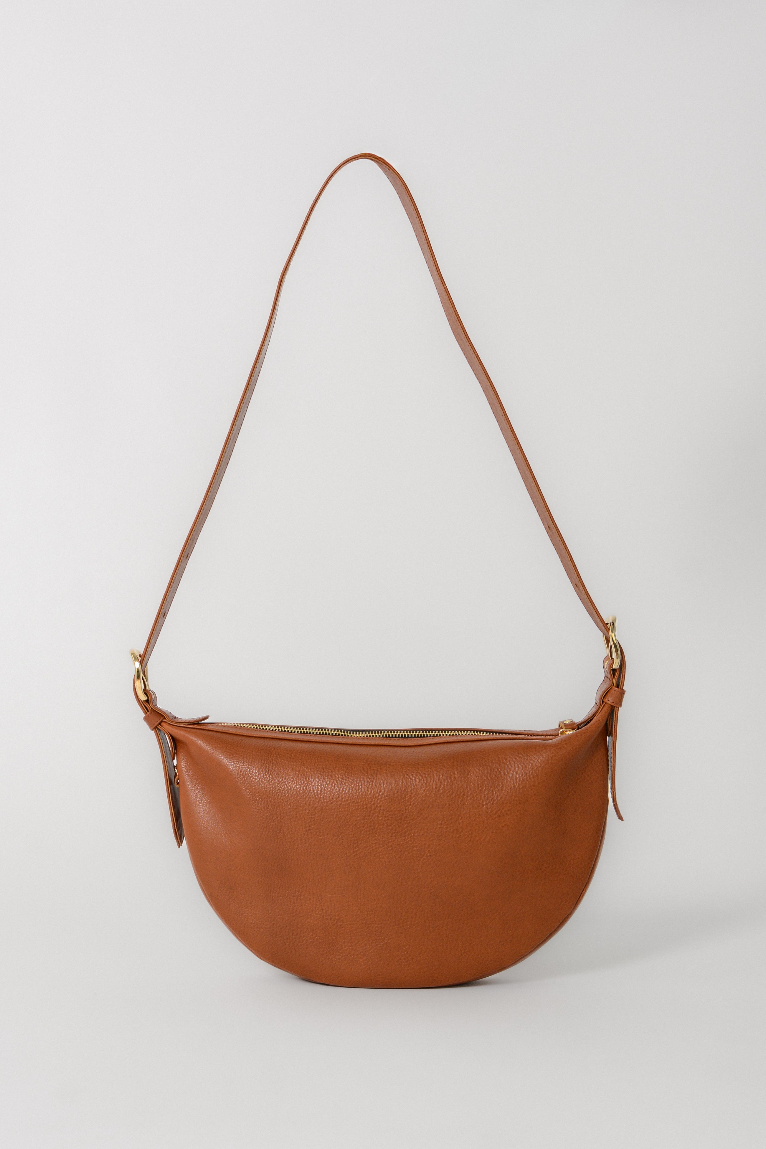 Cognac leather Nova Sling Bag with adjustable strap, worn as a crossbody or shoulder bag for everyday essentials.