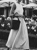Short video of a model carrying the black leather Phoebe bucket bag on the arm, styled with a flowing dress in an outdoor garden setting.